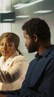 Vertical Supervisor in office discussing with employee about key performance indicators for revenue, profitability and operational efficiency. African american manager supervising employee at work, camera B video