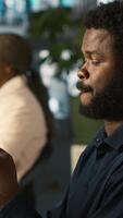 Vertical Employee in office taking break from checking documents to text friends using smartphone, relaxing. Accountant in office pausing tasks to answer messages on mobile phone, camera A video
