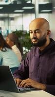 Vertical Happy man in office reviewing financial graphs, pleased after seeing good key performance indicators. Cheerful employee celebrating positive KPIs and data trends, camera B video