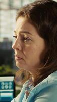 Vertical Worker in office falling asleep at computer desk while analyzing business performance metrics. Exhausted woman dozing off while reviewing financial charts at work, camera B video