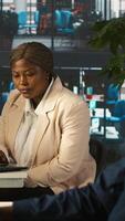 Vertical Employee in office showing revenue figures on laptop to manager. Accountant presenting company statistical numbers on notebook to supervisor after finishing job tasks, camera A video