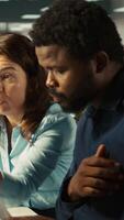 Vertical Team leader working together with bookkeeper to read and verify accuracy of business documents. Worker and manager analyzing company information records in office, camera B close up video