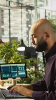 Vertical Accountant in office inputting financial figures on PC, giving report files to coworkers. Arab man in workplace crosschecking data on computer, giving documents to colleagues, camera B video