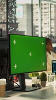 Vertical Green screen PC in office used by employee working on company administrative tasks. Mockup computer display on desk used by worker reviewing business data metrics, camera B video