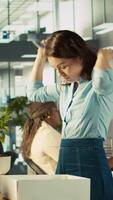 Vertical Upset worker in office packing desk plants on last day at work after quitting, saying goodbye to colleague. Employee getting fired from job during layoffs, saddening coworkers, camera B video