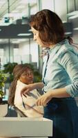 Vertical Employee getting consoled by colleagues after being fired, leaving office. Worker holding box filled with desk plants saying goodbye to coworkers after being laid off, camera B video