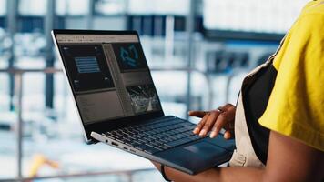 Solar panels plant worker tracking energy production through IoT sensors on notebook. Engineer in smart photovoltaics factory looking at system performance metrics on laptop, camera A close up video