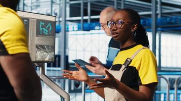 Engineering team in industry 4.0 industrial plant cooperating to install machinery, looking at monitor. Teamworking smart factory colleagues doing brainstorming to calibrate IoT sensors video