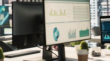 Financial charts and KPI metrics on displays in office, panning shot. Vibrant and collaborative modern workspace with computer screens displaying data analytics, close up shot video