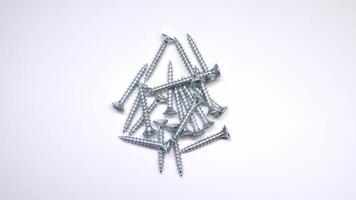 A collection of uniformly sized silver screws with sharp threads and flat countersunk heads arranged on a clean white background. video