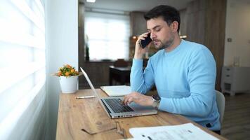 Working remotely in a cozy home office while multitasking with a phone call and laptop usage video