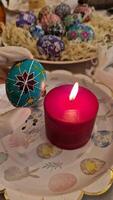 Expert artisans carefully create turquoise Easter egg featuring traditional Ukrainian pysanka patterns. Beeswax technique is applied for detailed designs while a red candle warming up handcrafted egg video