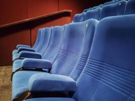 Rows of empty blue seats in a cinema hall for a large number of people. Cinema and theater halls for watching shows. photo