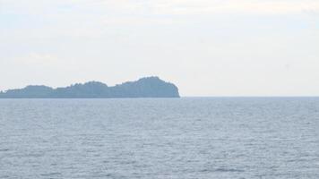 The ocean is calm and the waves are small. The water is a beautiful shade of blue. The sky is clear and the sun is shining photo