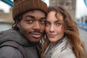 A smiling Black man and a Caucasian woman pose closely together outdoors, showcasing their connection against a blurred urban backdrop. photo
