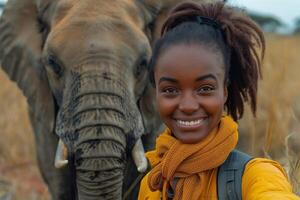 Smiling Black woman takes a selfie with a friendly elephant in a golden grassland setting. photo
