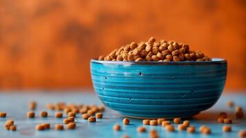 A vibrant blue bowl filled with small, round dog food biscuits against an orange backdrop, creating a warm and inviting atmosphere. photo