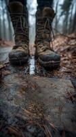 Close-up of rugged boots standing on a wet stone path in a misty forest, highlighting the adventure of hiking in nature. photo