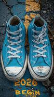 Close-up of vibrant blue sneakers with worn-out soles on a cracked asphalt path marked with a yellow line. photo