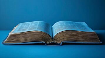 An open book with yellowed pages lies on a light blue background, showcasing its intricate text and aged appearance. photo