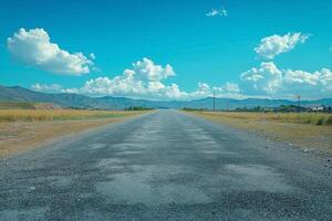 A serene rural road stretches into the horizon under a vibrant blue sky filled with fluffy white clouds. photo