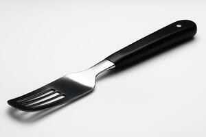 A sleek stainless steel serving fork with a modern black handle, perfect for elegant dining. photo