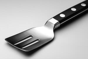 A sleek, modern stainless steel spatula with a black handle, ideal for cooking and grilling. photo