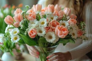 A woman with long hair presents a stunning bouquet of peach tulips and white daisies, creating a gentle, elegant atmosphere. photo