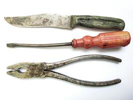 Aged tools a knife, screwdriver, and pliers, arranged on a white background. Evokes nostalgia, DIY, and craftsmanship. Perfect for projects about repair, vintage items, or manual labor. photo