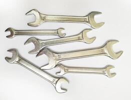 A collection of shiny metal wrenches scattered on a white background. This image conveys concepts of repair, maintenance, DIY, and problemsolving. photo