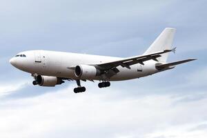 A large white cargo airplane captured during its landing approach against a cloudy sky. photo