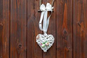 Decorative heart-shaped ornament hanging from wooden wall showcasing intricate design with natural elements photo