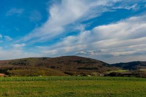 Scenic view of lush hills and blue sky during the afternoon in a quiet countryside landscape photo