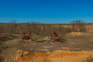 Abandoned mining equipment in a barren landscape during bright daylight at a remote location photo
