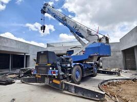 A large auto crane is parked right in front of a building that is currently under construction photo