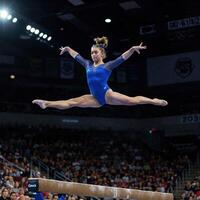 A female gymnast is doing a split on the balance beam photo