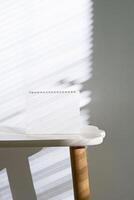 Blank Calendar on the Table with Light from Blinds. Modern Template Mockup for Invitations and Promotions. photo