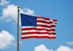 Patriotic flag waving against a blue sky with clouds photo