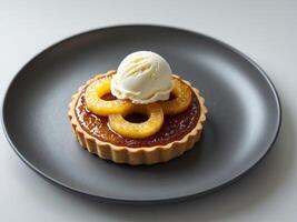 Delicious caramelized pineapple tart with creamy vanilla ice cream served on a dark plate. photo