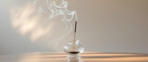 An incense stick burning in a decorative glass on a table photo