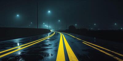 A long empty road at night with yellow lines photo
