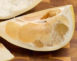 fresh, juicy slice of pomelo fruit with visible pulp and peel. Citrus fruit section on wooden table photo