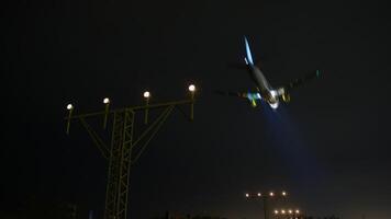 Illuminated airport approach lighting system guiding passenger airplane descending at night, providing critical navigation and safety guidance during landing sequence video