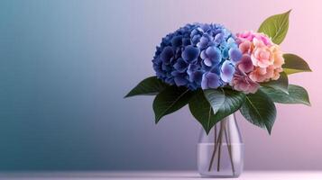 Vase of blue and pink flowers sits on a table. The flowers are in a clear vase and are surrounded by green leaves photo