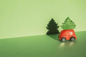 Red toy car with a christmas tree on the roof, green background photo