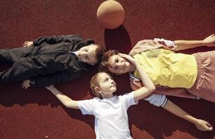 Laid-back Laughter. Unwinding with Children on the Basketball Court Surface with mother photo