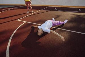 Laid-back Laughter. Unwinding with Children on Basketball Court Surface with mother photo