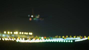 Airplane approaching illuminated runway, blending motion blurred lights with darkening sky during nocturnal airport descent video