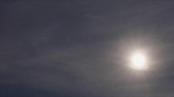 Passenger airplane descending with sun backlighting, silhouetted against bright sky during dramatic slow motion landing sequence video