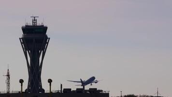 Large passenger aircraft ascending from airport runway, climbing swiftly past control tower silhouetted against dusky sky while gaining altitude and flying away toward distant horizon video